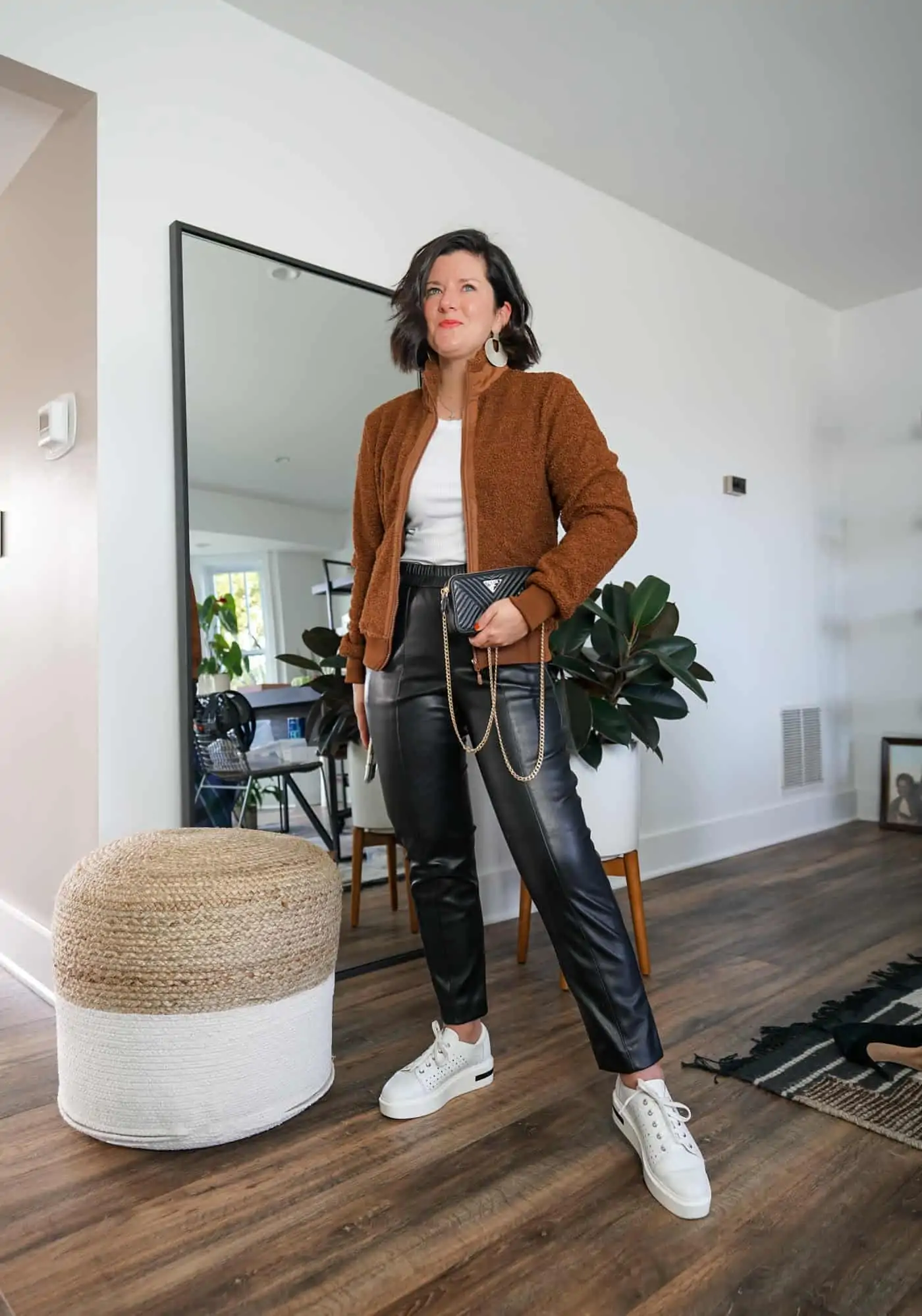 A Lily Love Affair wearing womes faux leather pants with a brown sherpa jacket and white sneakers