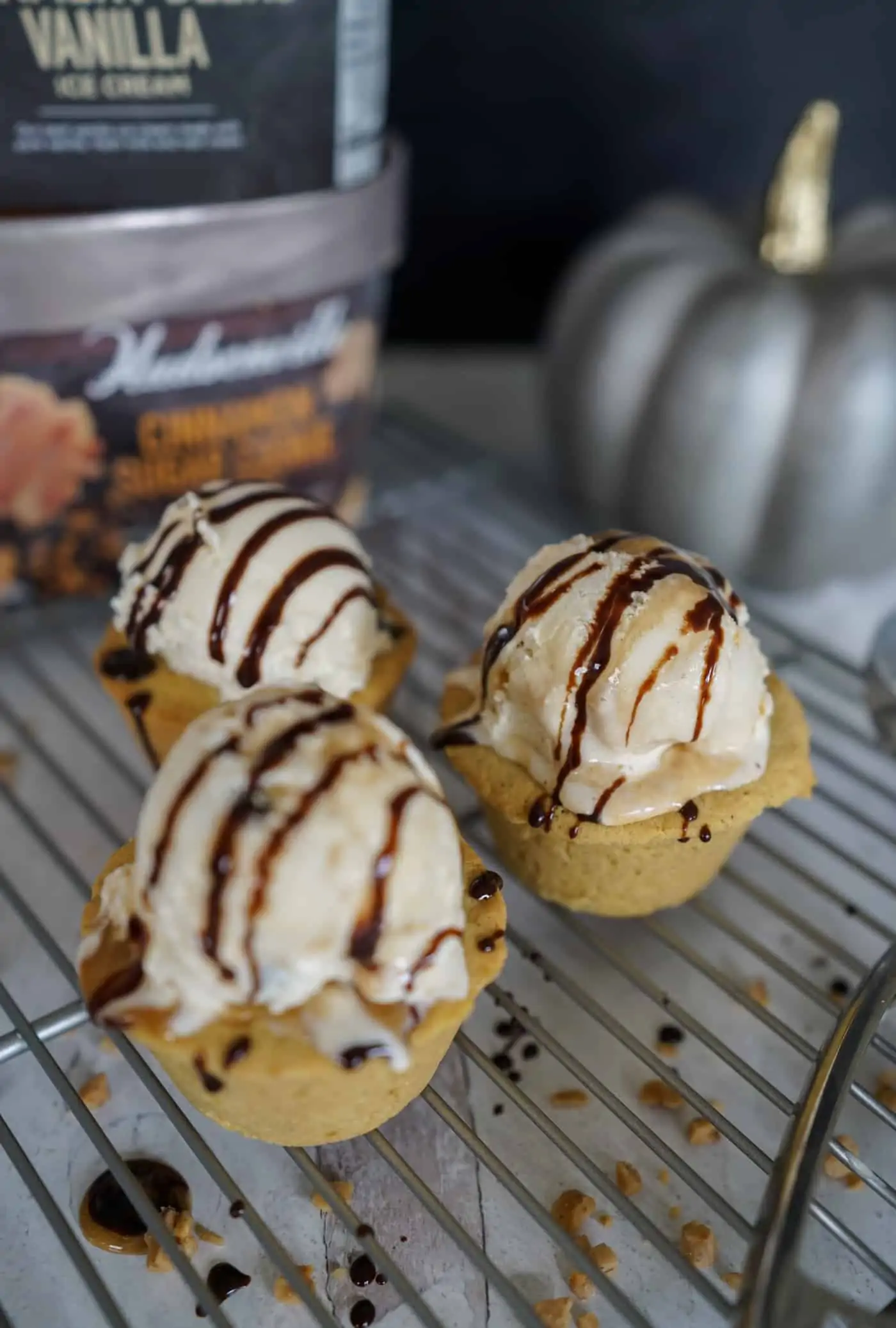 Three pumpkin spice cookie cups topped with a scoop of Hudsonville ice cream and chocolate suace