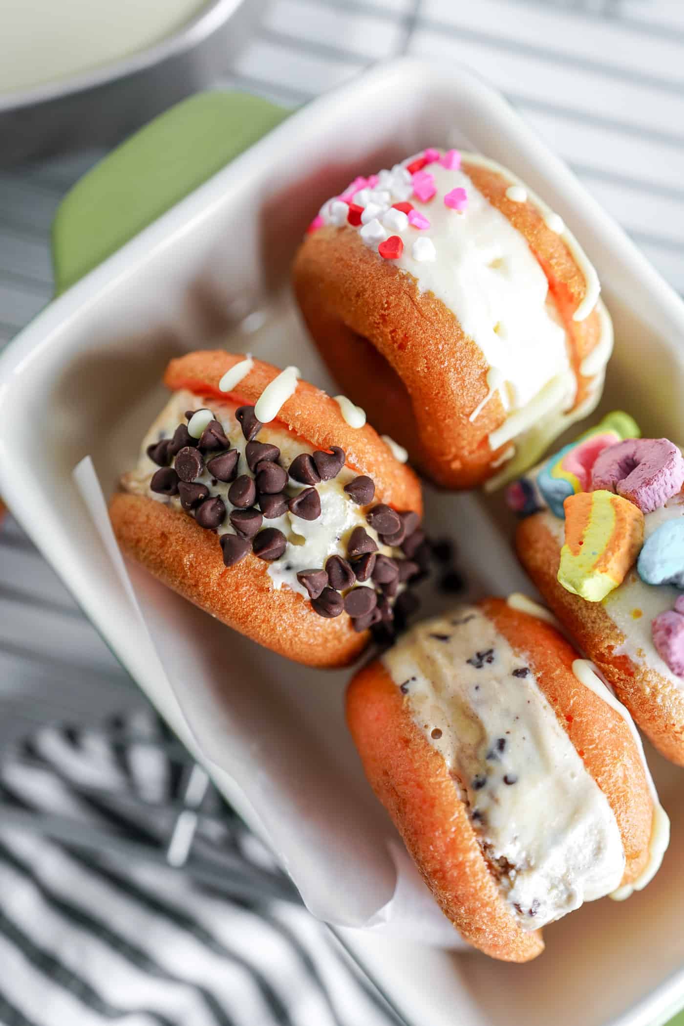 Four donut ice cream sandwiches in a small bowl with chocolate chunks