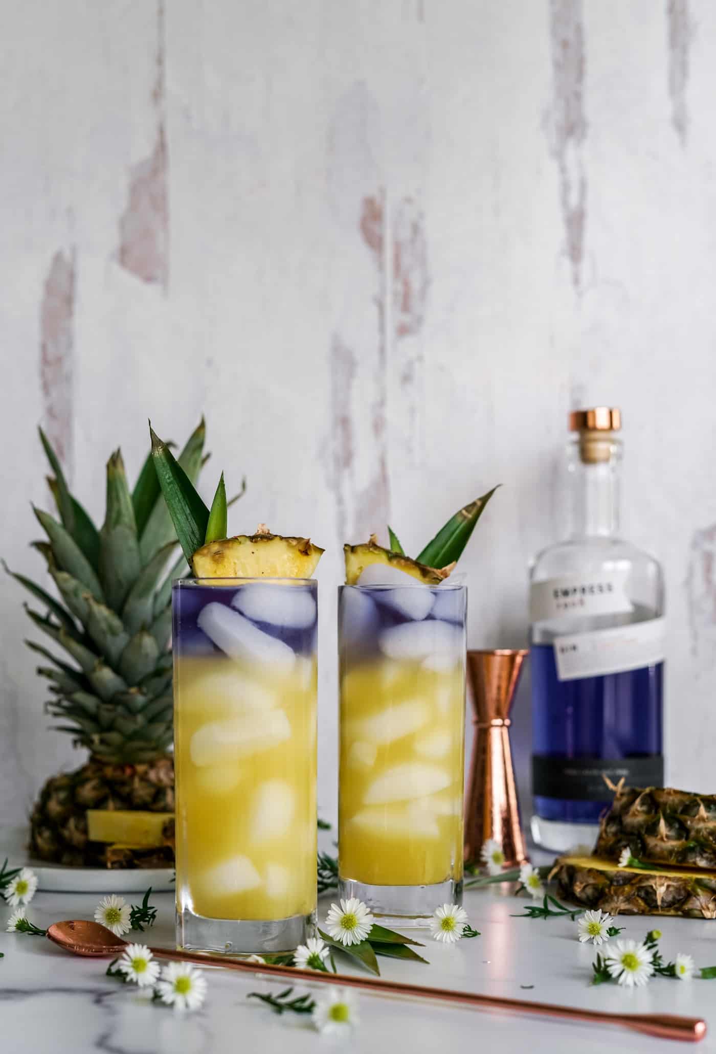 Two tall collins glasses filled with a royal hawaiian cocktail made with empress gin