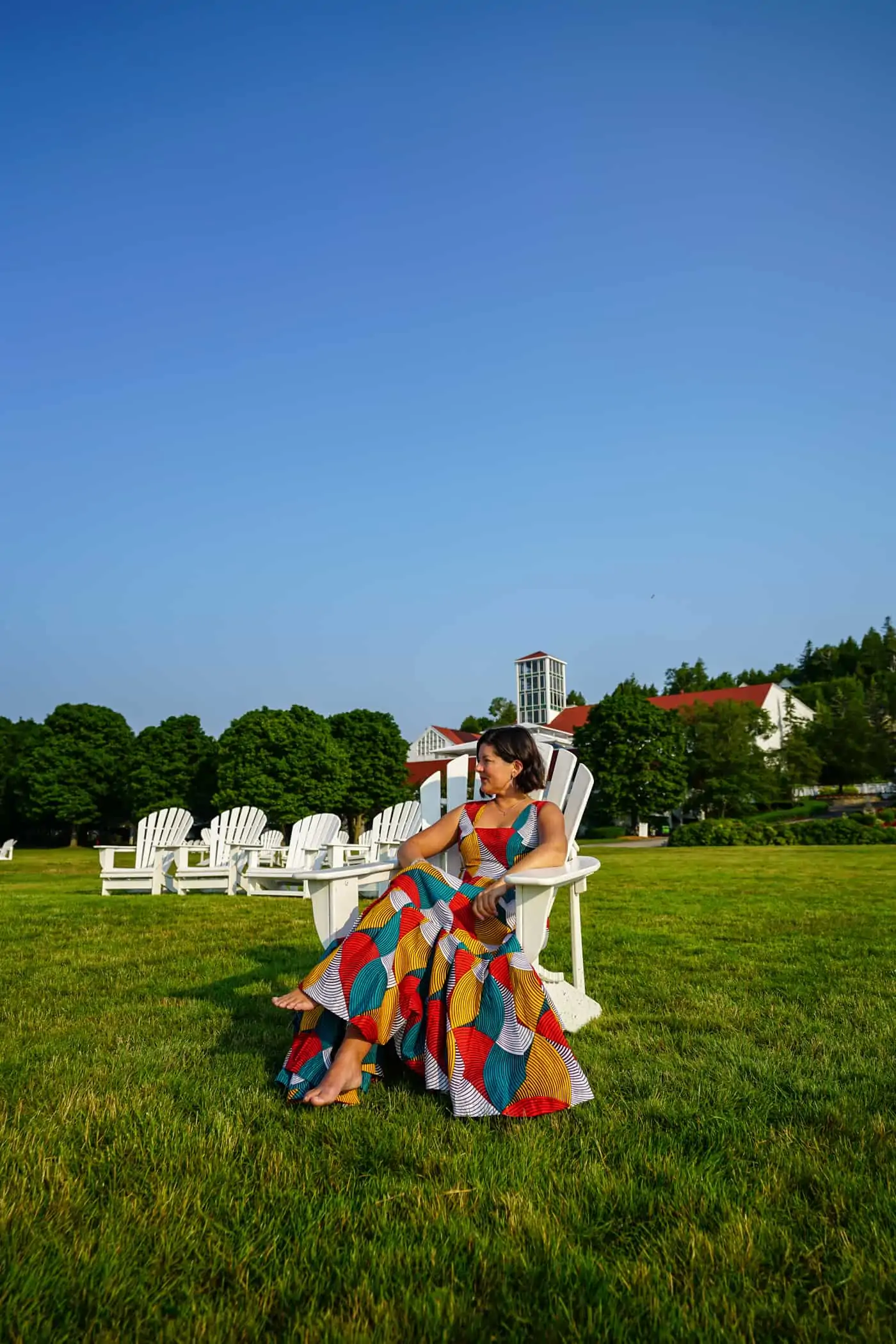 A women in a dress in an adirondack chair on the lawn of Mission Point Resort