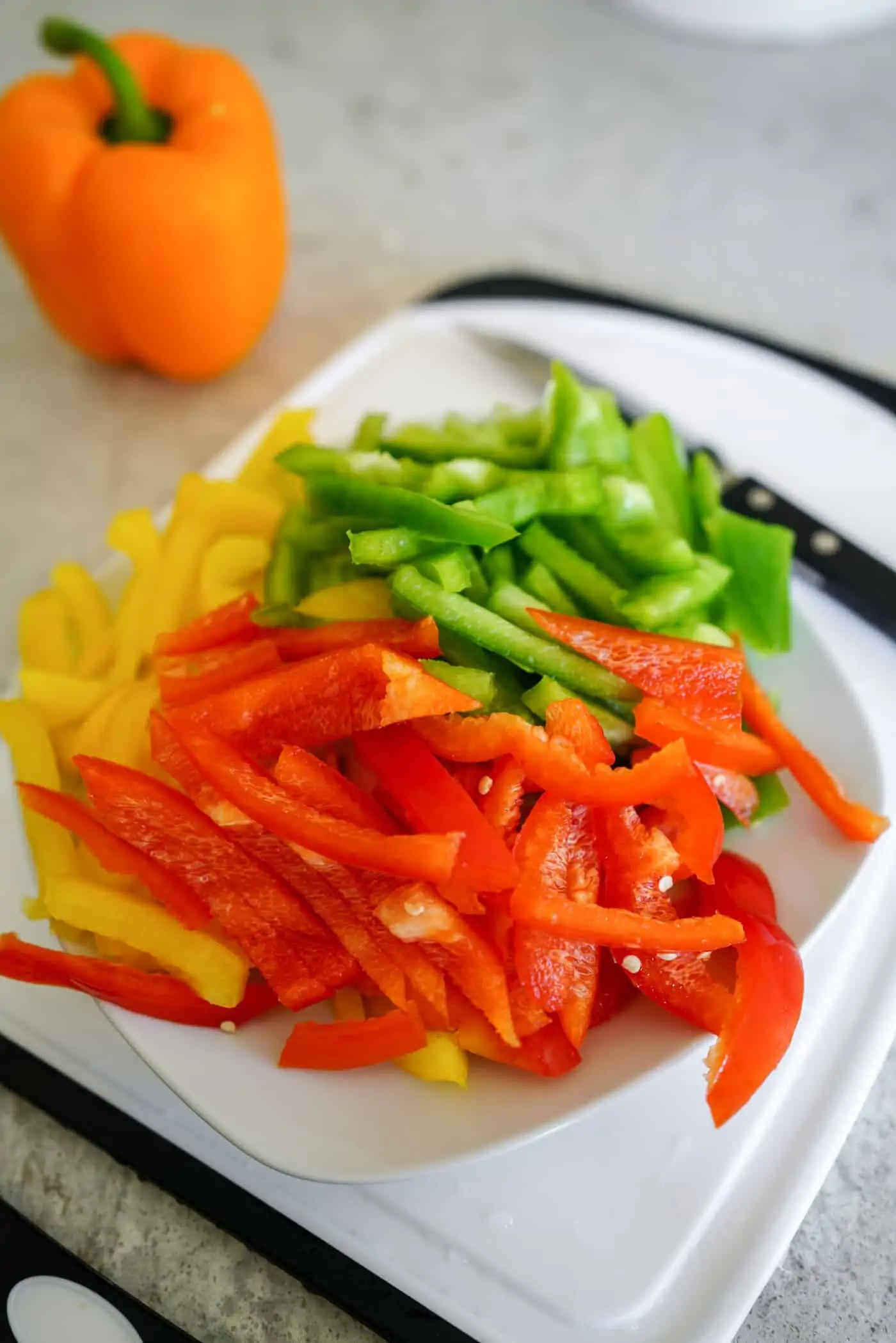 A plate filled with chopped red, green and yellow bell peppers for Instant Pot Chicken Fajita Pasta recipe. 