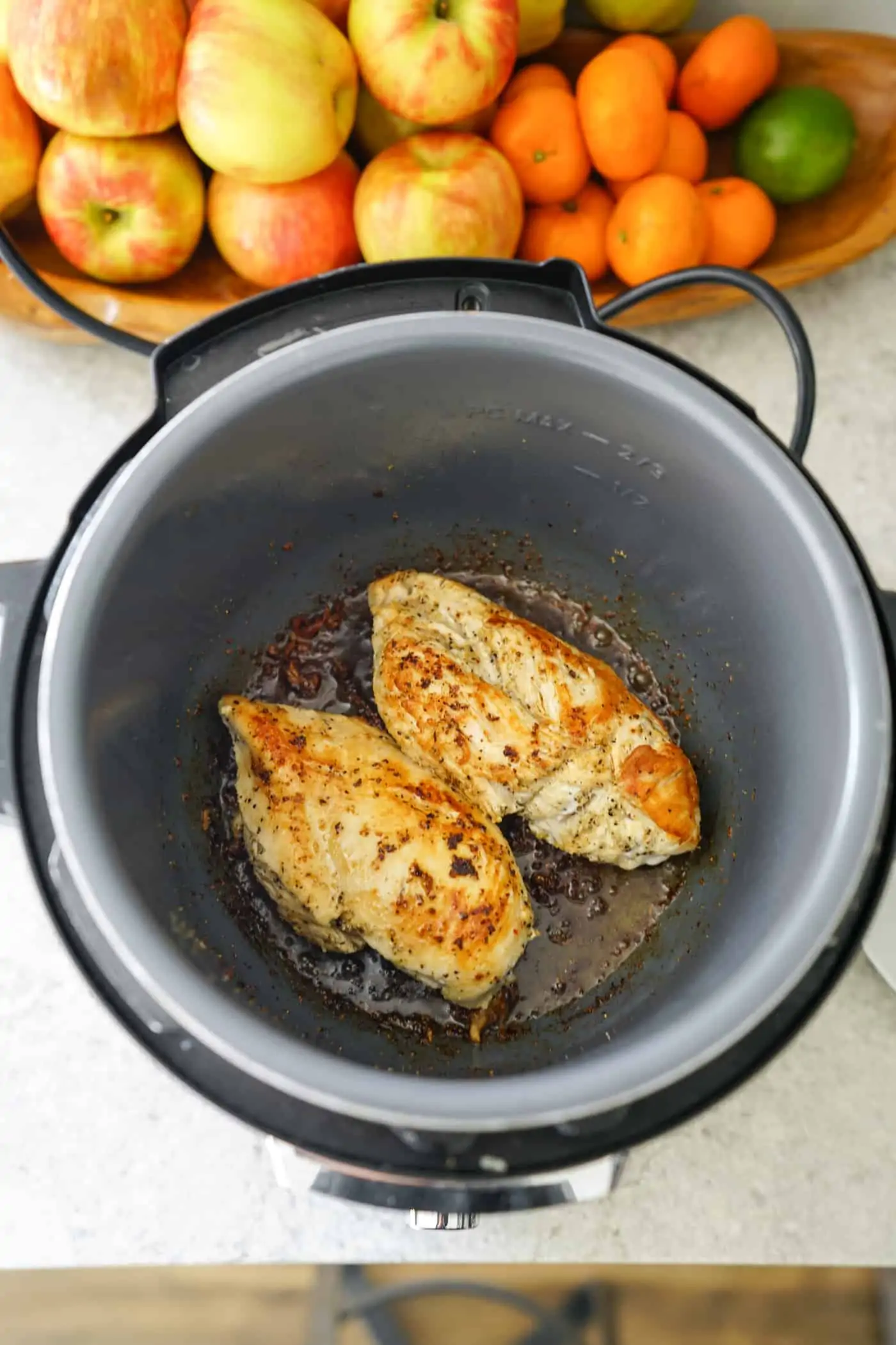 An Instant Pot with two boneless chicken breasts on the saute mode.  
