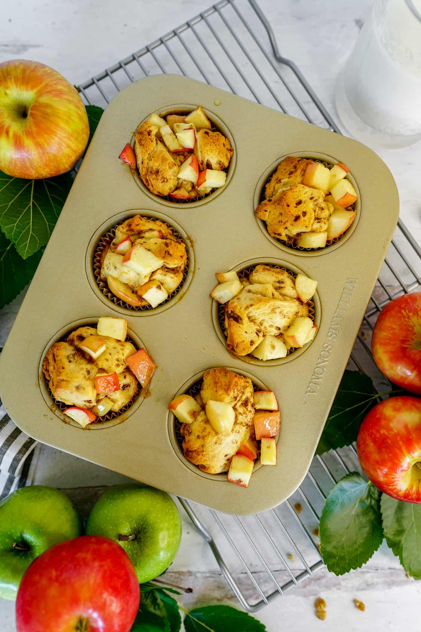 One nonstick muffin tin filled with uncooked monkey bread muffins with apples.  