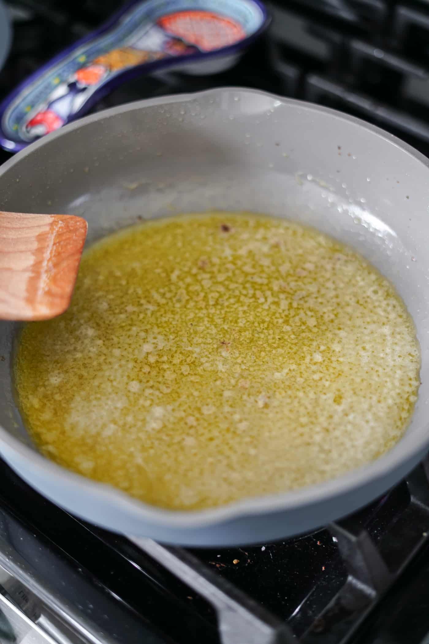 An Our Place Always Pan on the stove wtih cooking butter for a sun-dried tomato alfredo pasta recipe. 