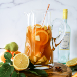 A large glass pitcher filled with Thanksgiving sangria recipe and fresh fruit chunks.